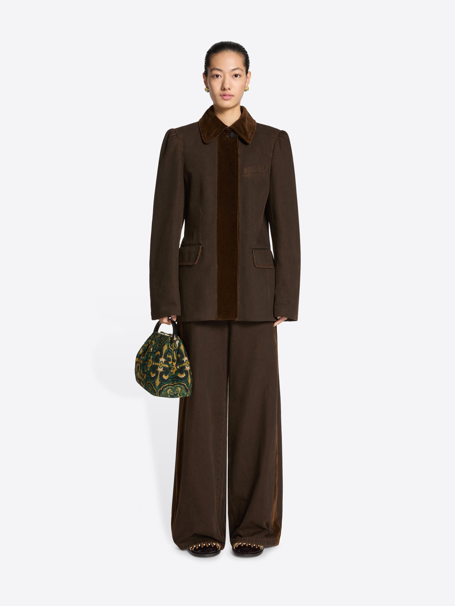 Person wearing a brown collared jacket and pants ensemble on a white background