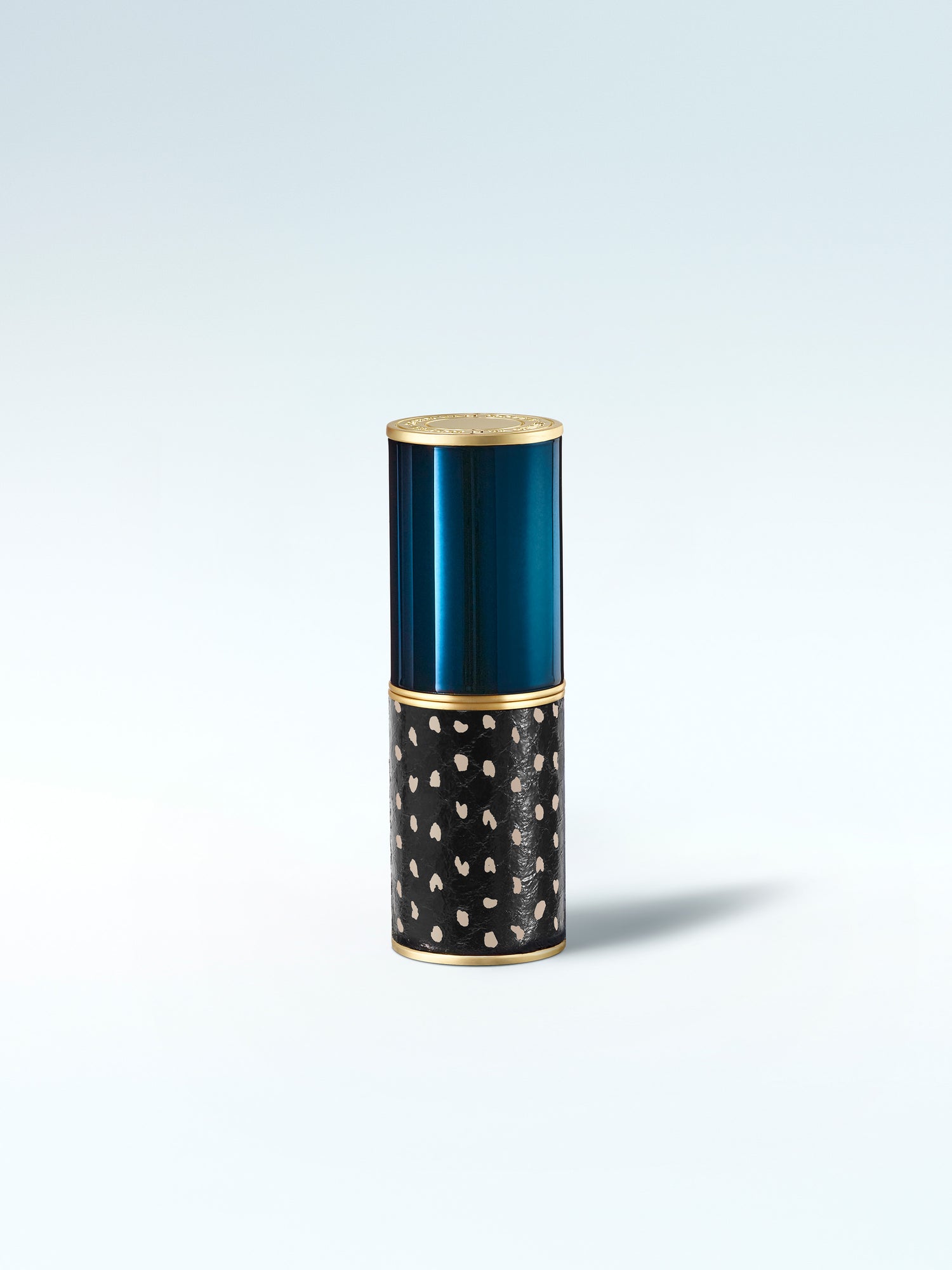 Decorative cylindrical container with blue top and black base with white patterns on a light gray background