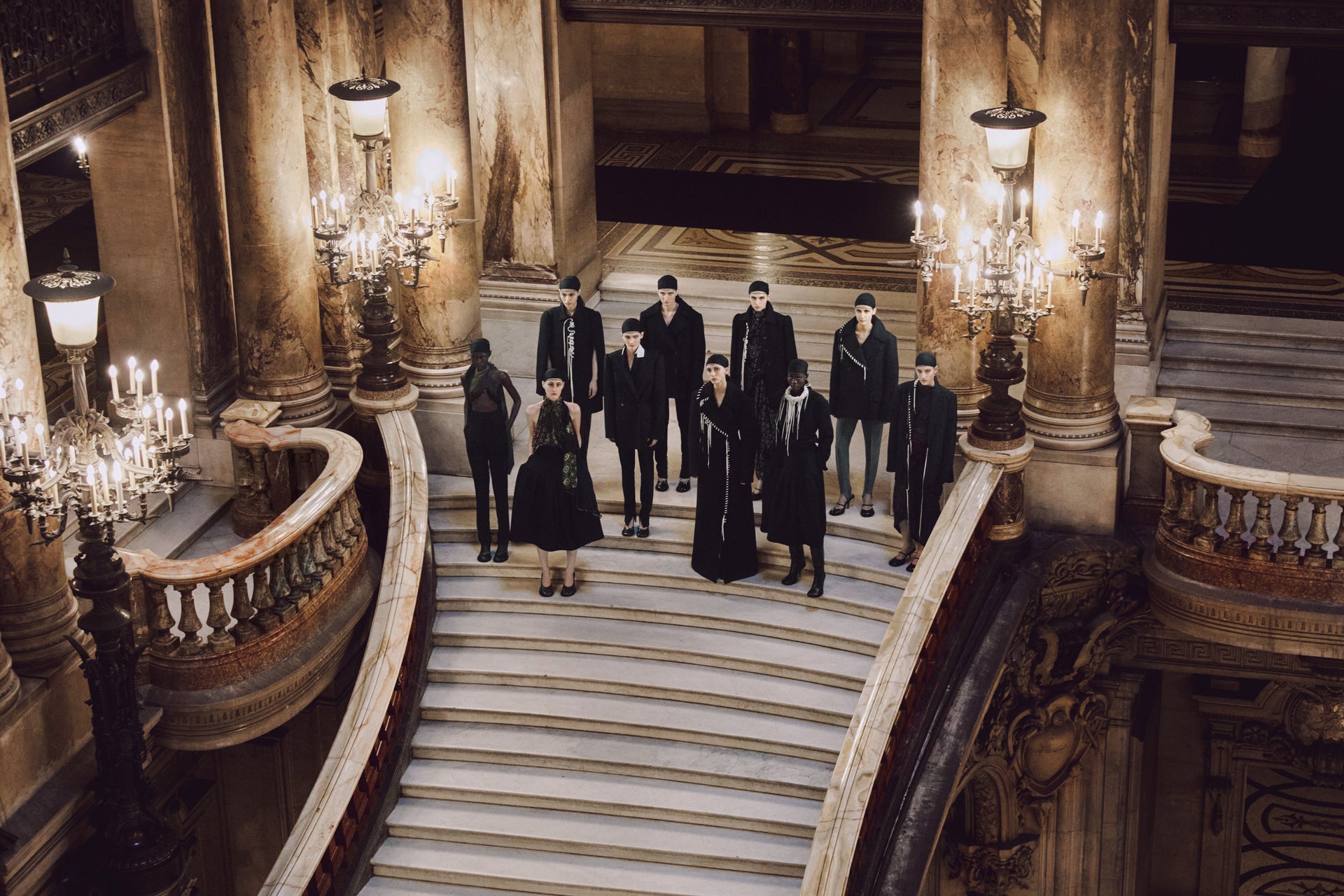 Group of people in formal attire standing on a grand staircase in an opulent building.