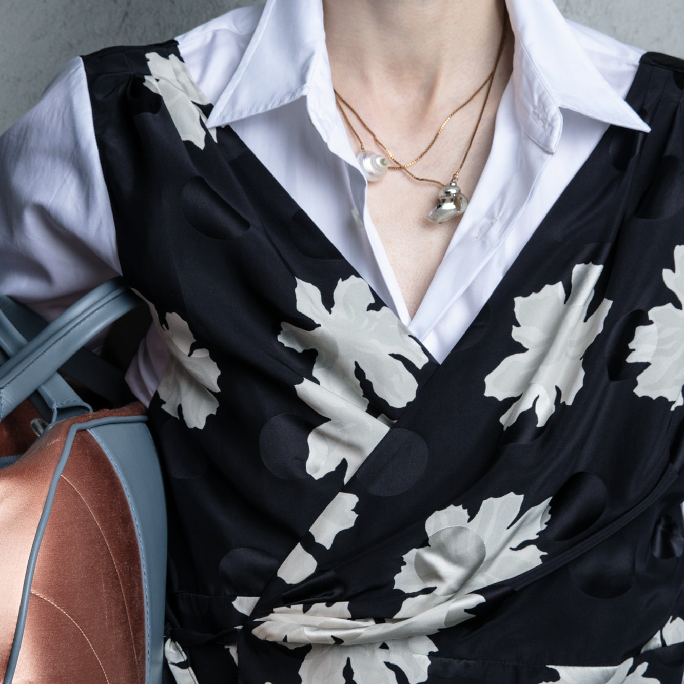 Person wearing a black floral patterned top over a white shirt with a gray background - Dries Van Noten