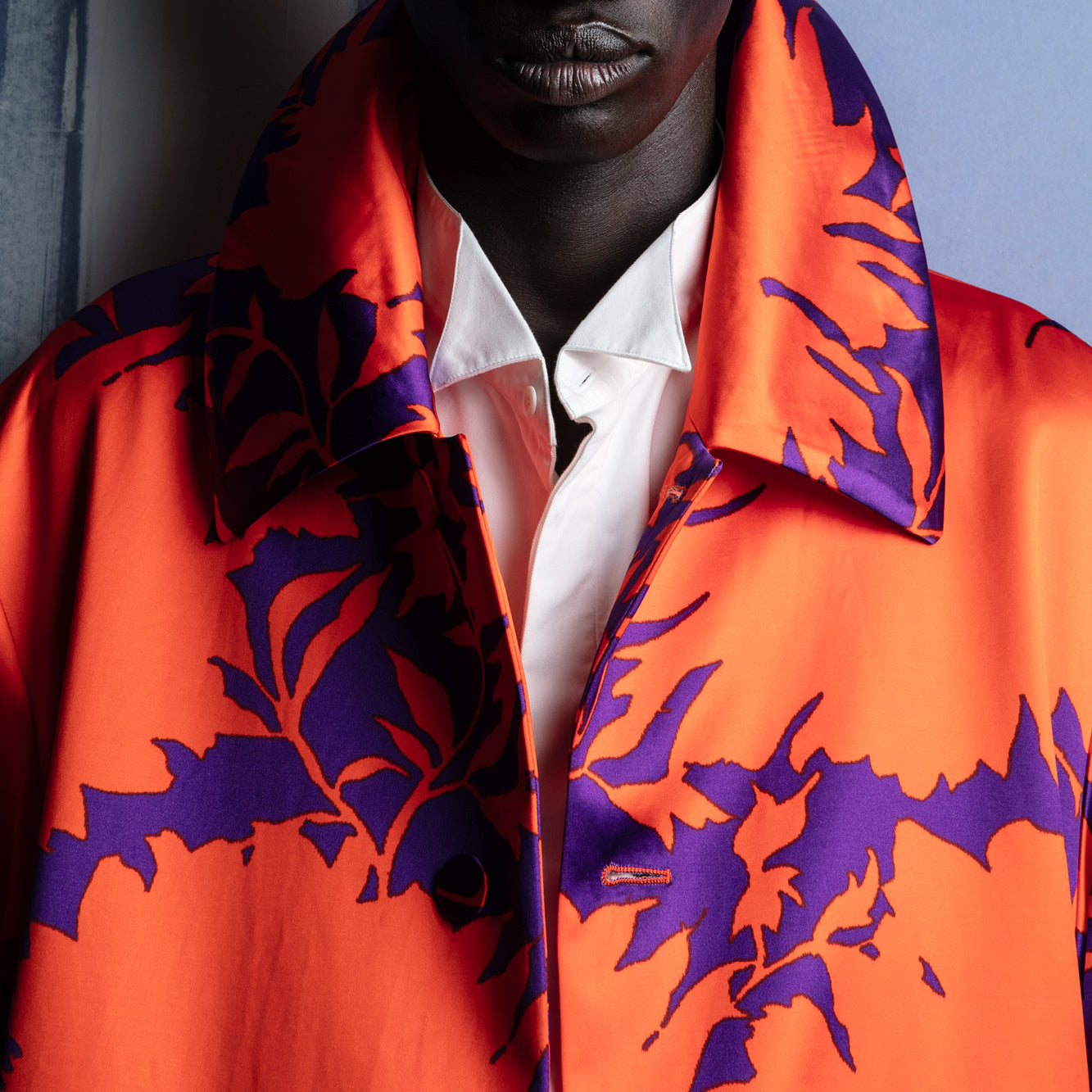 Person wearing a vibrant orange and purple patterned jacket over a white shirt - Dries Van Noten