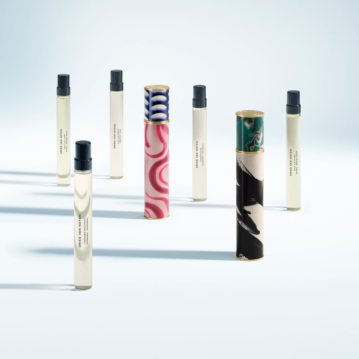 Set of small cylindrical containers with black caps on a light gray background - Dries Van Noten