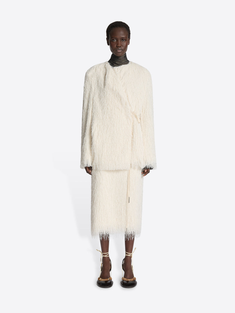 Person wearing a white fluffy coat and skirt on a white background