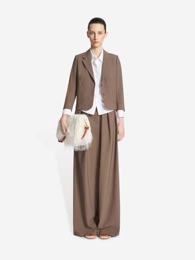 Person wearing a taupe tight fit cropped blazer with patch pockets while holding a white handbag, on a white background - Dries Van Noten