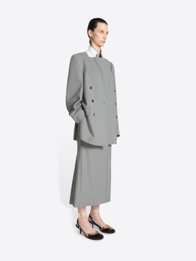 Person wearing a gray double breasted blazer and skirt set on a white background