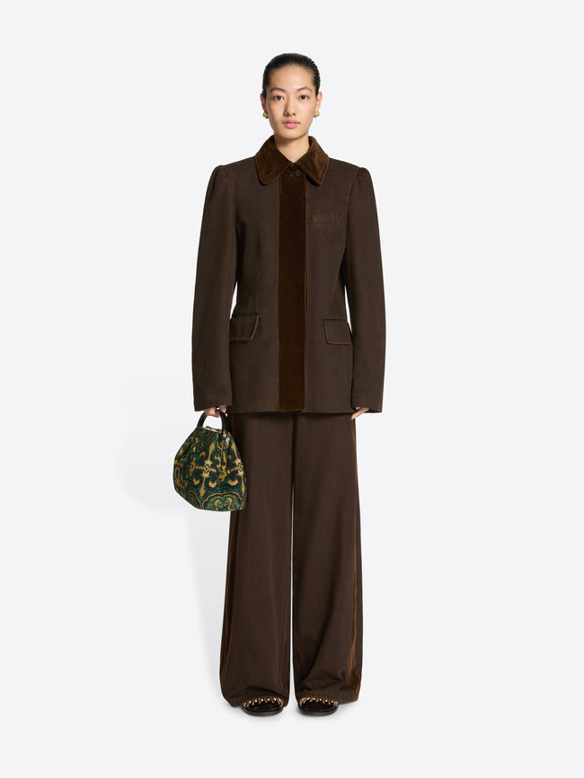 Person wearing a brown collared jacket and pants ensemble on a white background