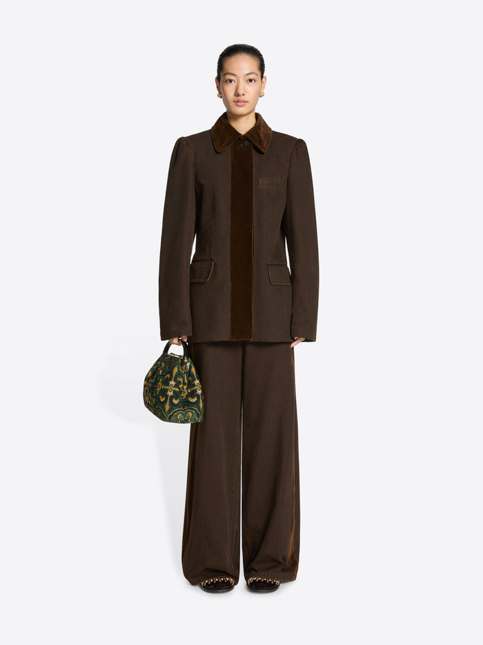 Person wearing a brown collared jacket and pants ensemble on a white background