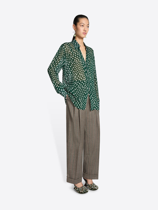 Person wearing a green and white patterned blouse on a white background