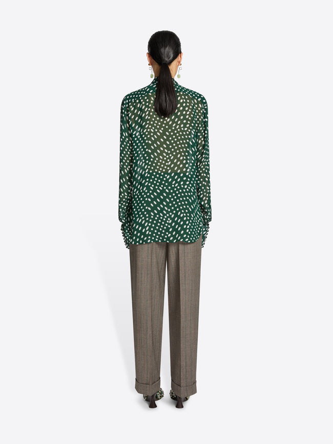 Person wearing a green and white patterned blouse on a white background