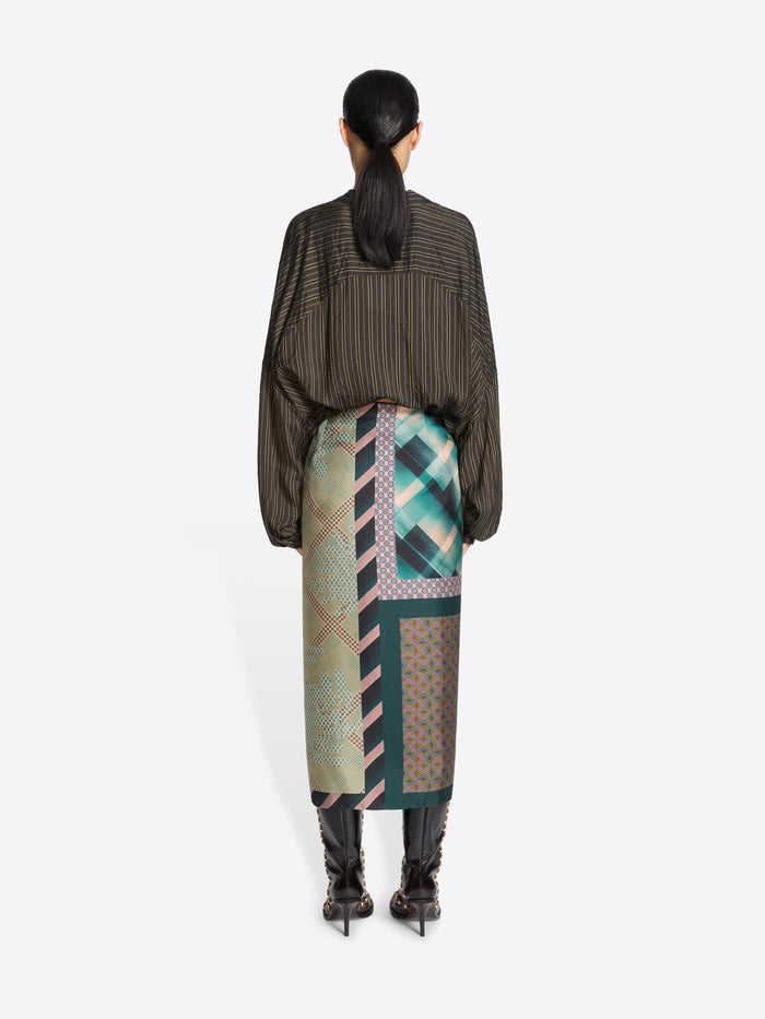 Person wearing a patterned outfit with a long skirt on a white background