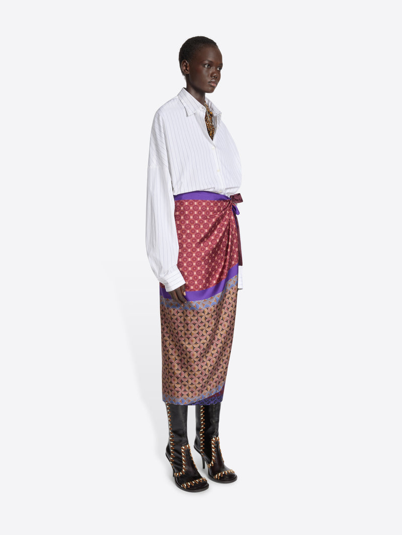 Model wearing a white shirt and multi-colored patterned skirt on a white background