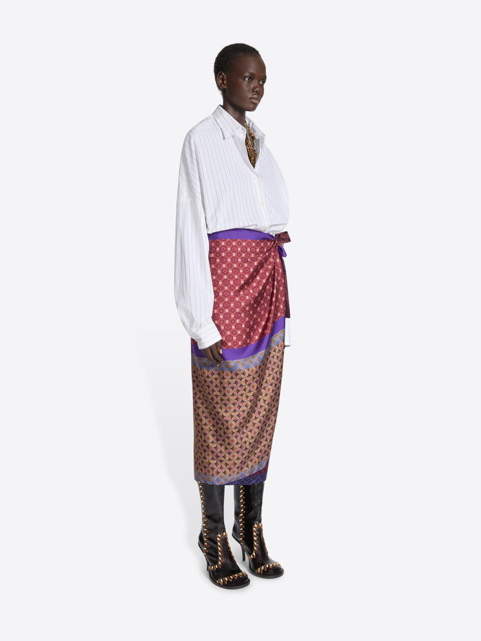 Model wearing a white shirt and multi-colored patterned skirt on a white background