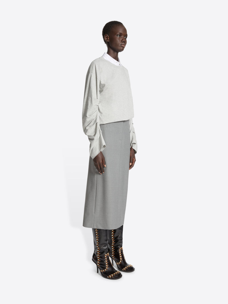 Person wearing a white blouse, gray skirt, and black boots on a white background