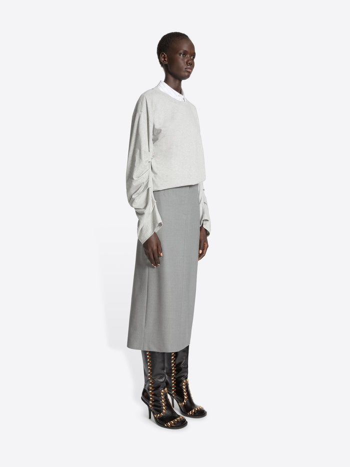 Person wearing a white blouse, gray skirt, and black boots on a white background