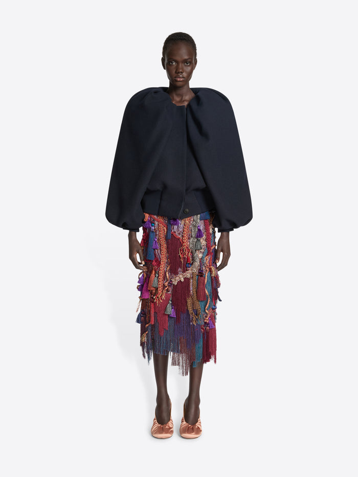 Person wearing a navy balloon top and a multicoloured, burgundy embellished skirt on a white background