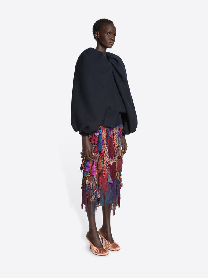 Person wearing a navy balloon top and a multicoloured, burgundy embellished skirt on a white background