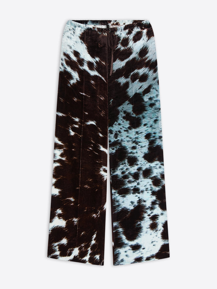 Wide-leg, elasticated pants with a black and white cowhide motif on a white background