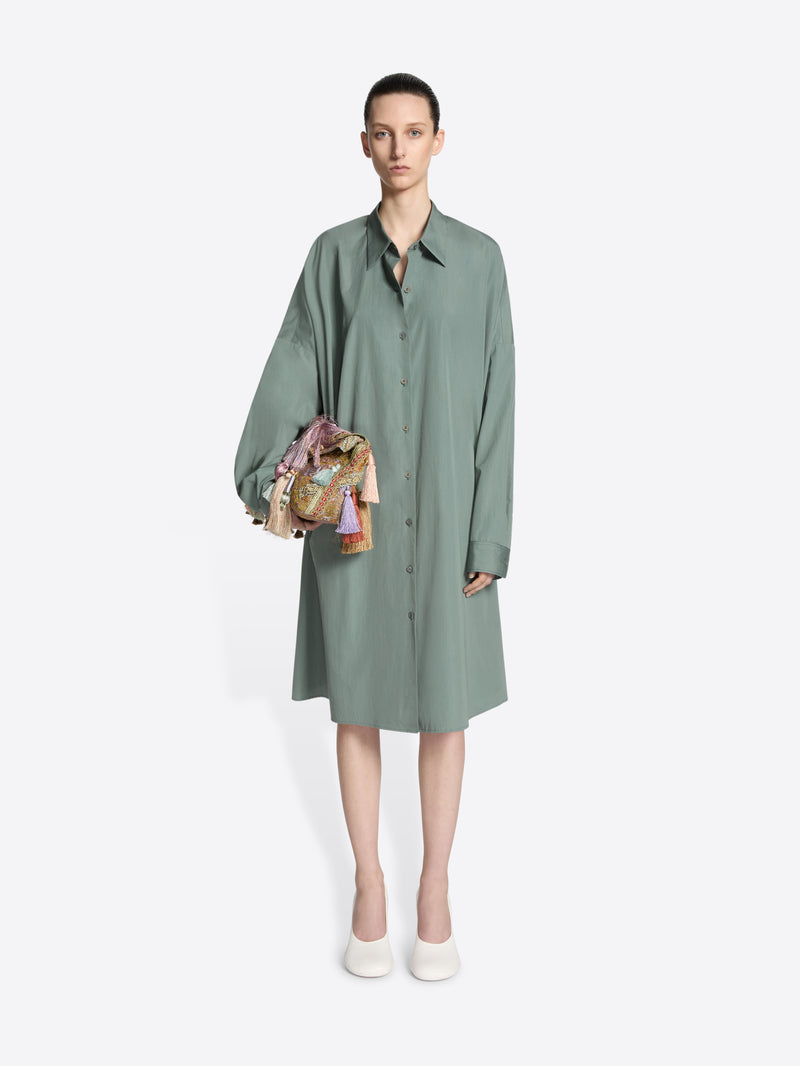 Model wearing a raf colored, oversized cotton shirt dress while wearing an embellished bag on a white background