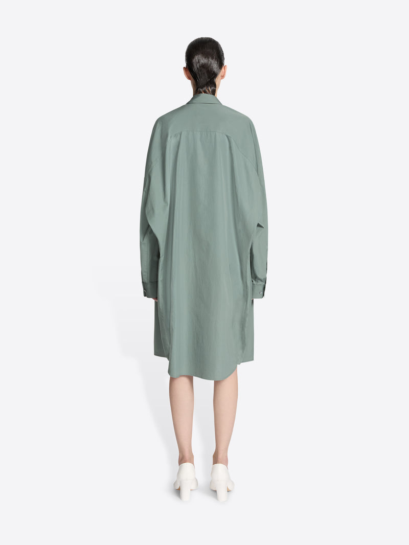 Backside of a model wearing a raf colored, oversized cotton shirt dress on a white background