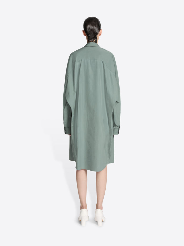 Backside of a model wearing a raf colored, oversized cotton shirt dress on a white background