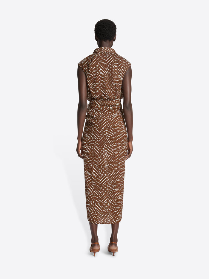 Model wearing a brown patterned dress on a white background