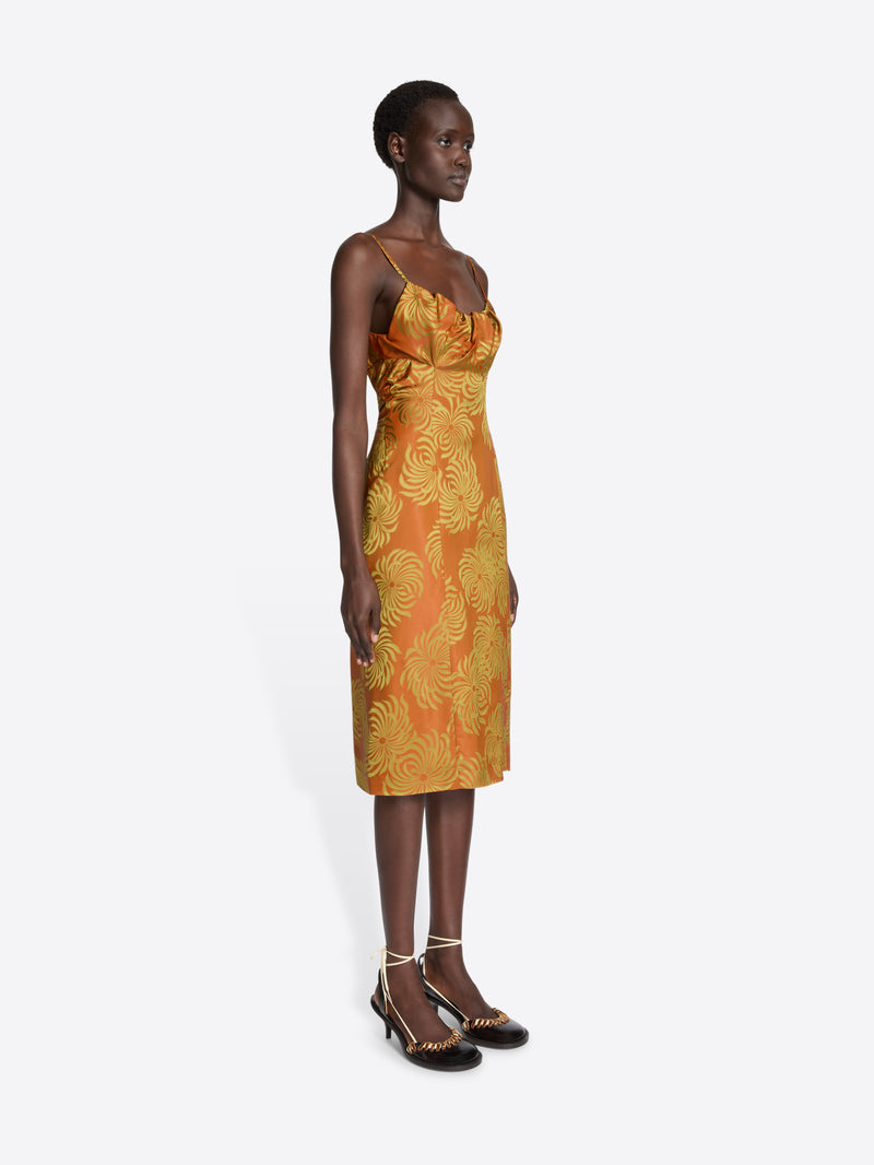 Woman wearing an orange dress with yellow floral pattern on a white background
