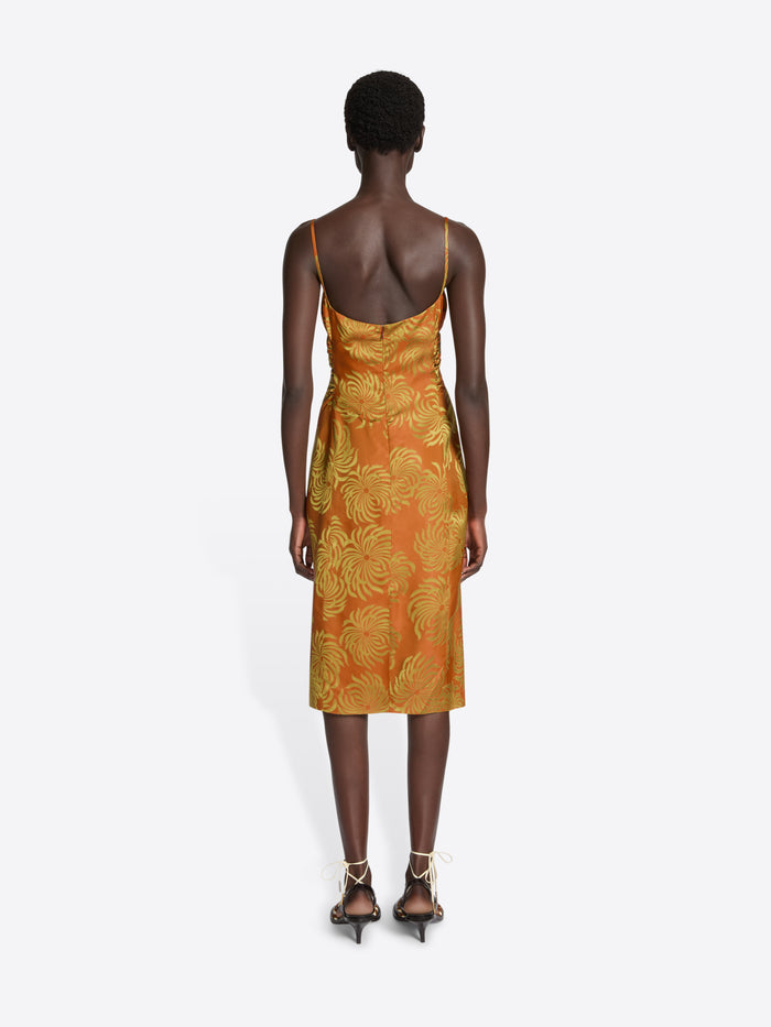 Woman wearing an orange dress with yellow floral pattern on a white background