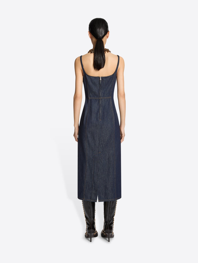 Person wearing a denim dress with thin straps on a white background