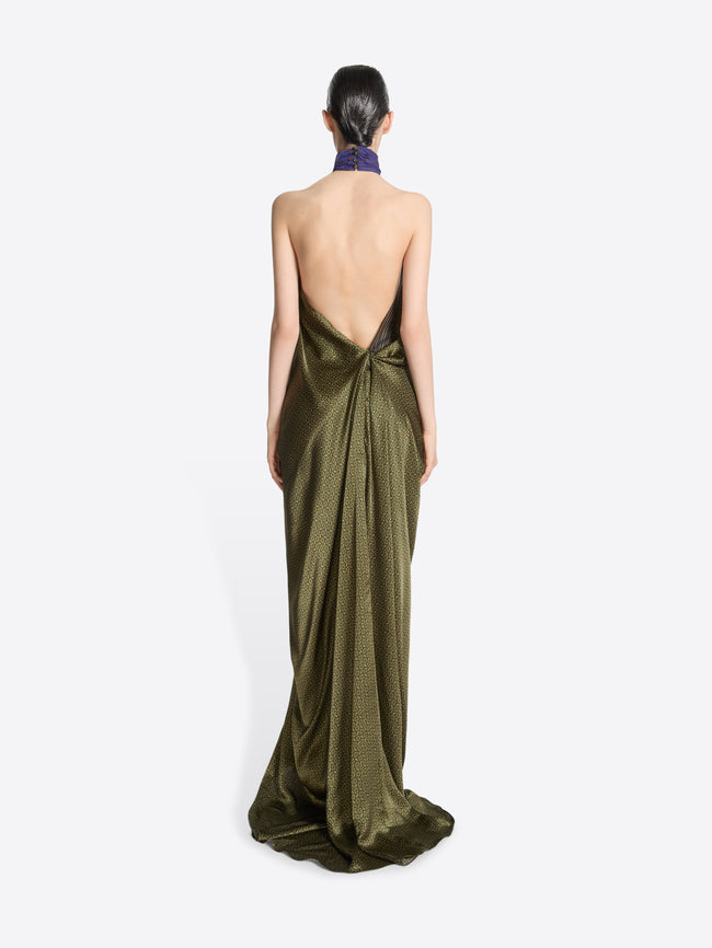 Woman wearing a long, dark green evening gown with a low back on a white background