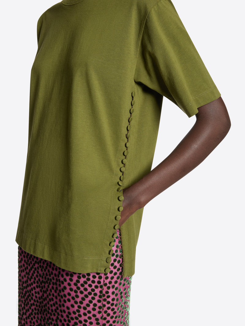 Person wearing a green t-shirt with a side slit on a white background