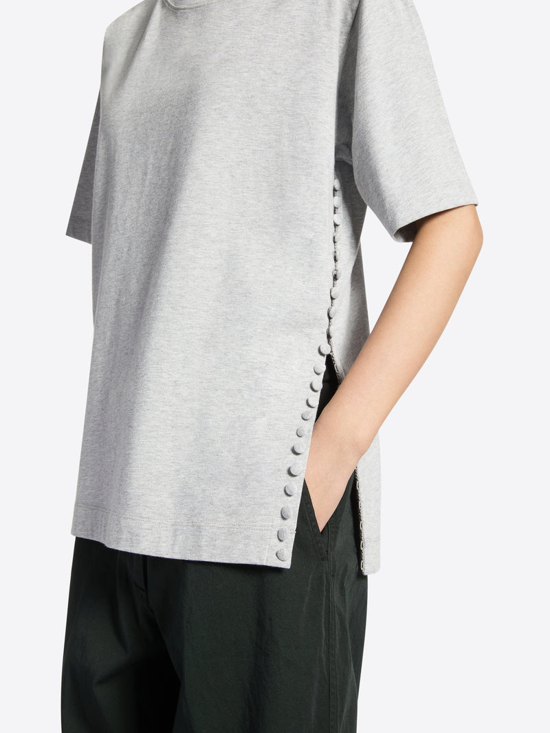 Person wearing a gray t-shirt with slit on a white background