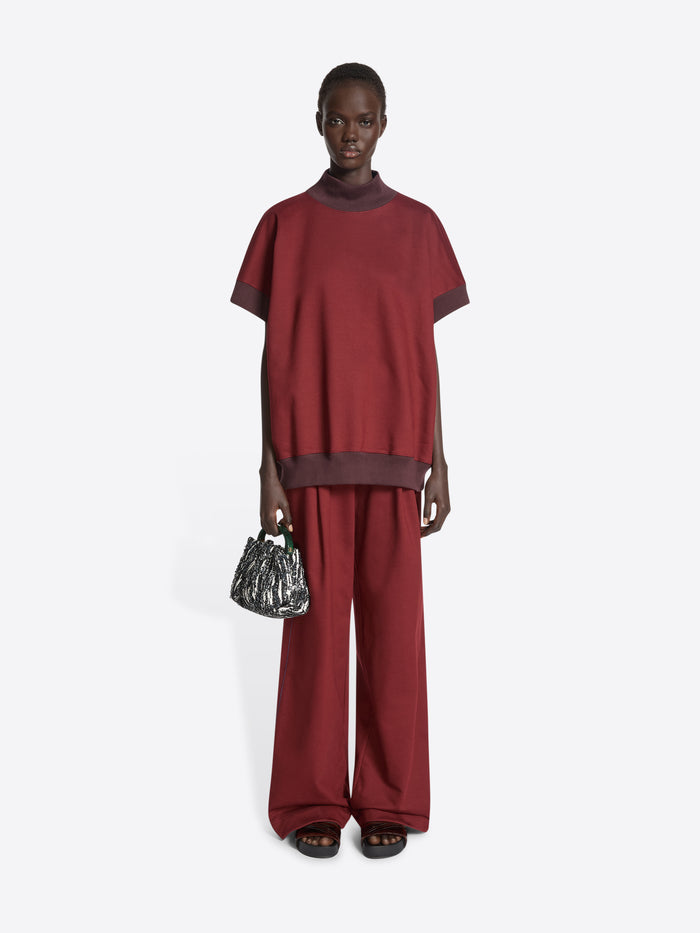 Person wearing maroon wide-leg pants on a white background