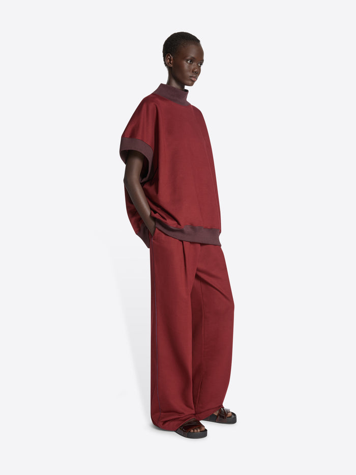 Person wearing maroon wide-leg pants on a white background