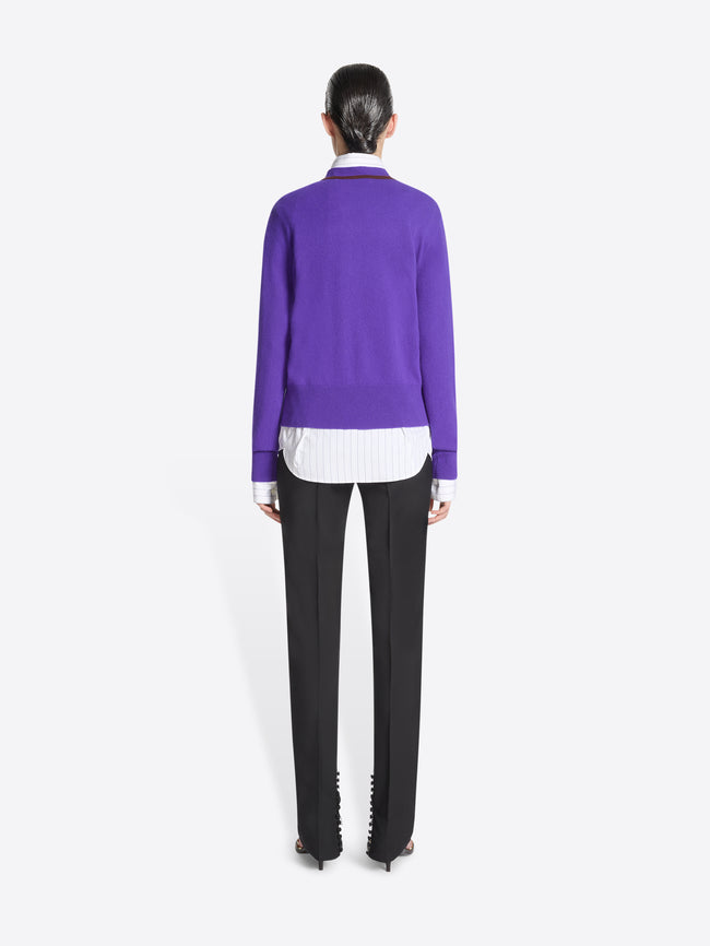 Person wearing a purple sweater with brown trim on a white background