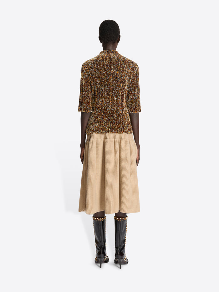 Person wearing a beige ribbed pleated skirt on a white background