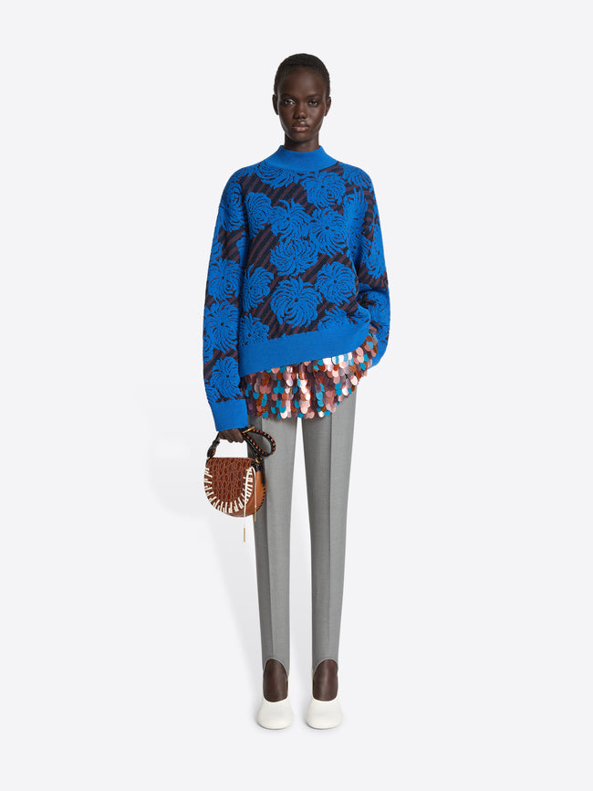 Person wearing a blue sweater with flower pattern on a white background