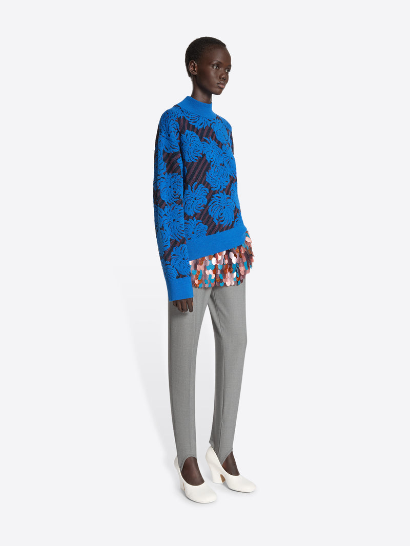 Person wearing a blue sweater with flower pattern on a white background
