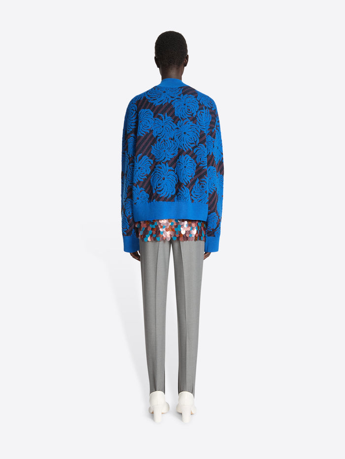 Person wearing a blue sweater with flower pattern on a white background