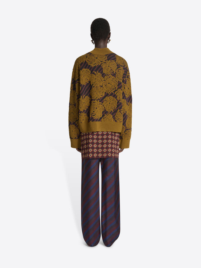 Person wearing a brown sweater with floral pattern on a white background