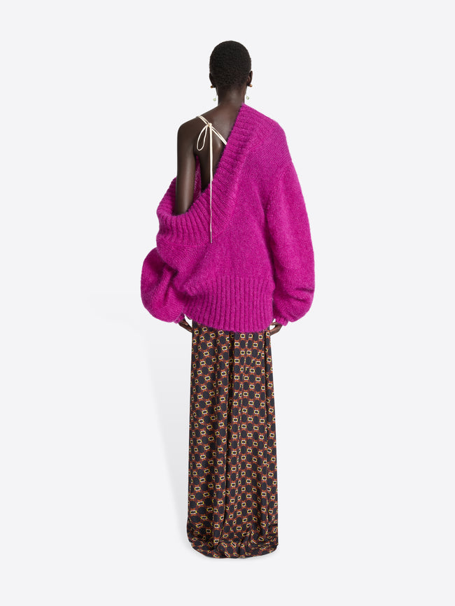 Person wearing a pink off-shoulder sweater on a white background