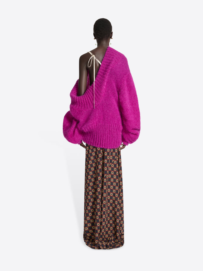 Person wearing a pink off-shoulder sweater on a white background