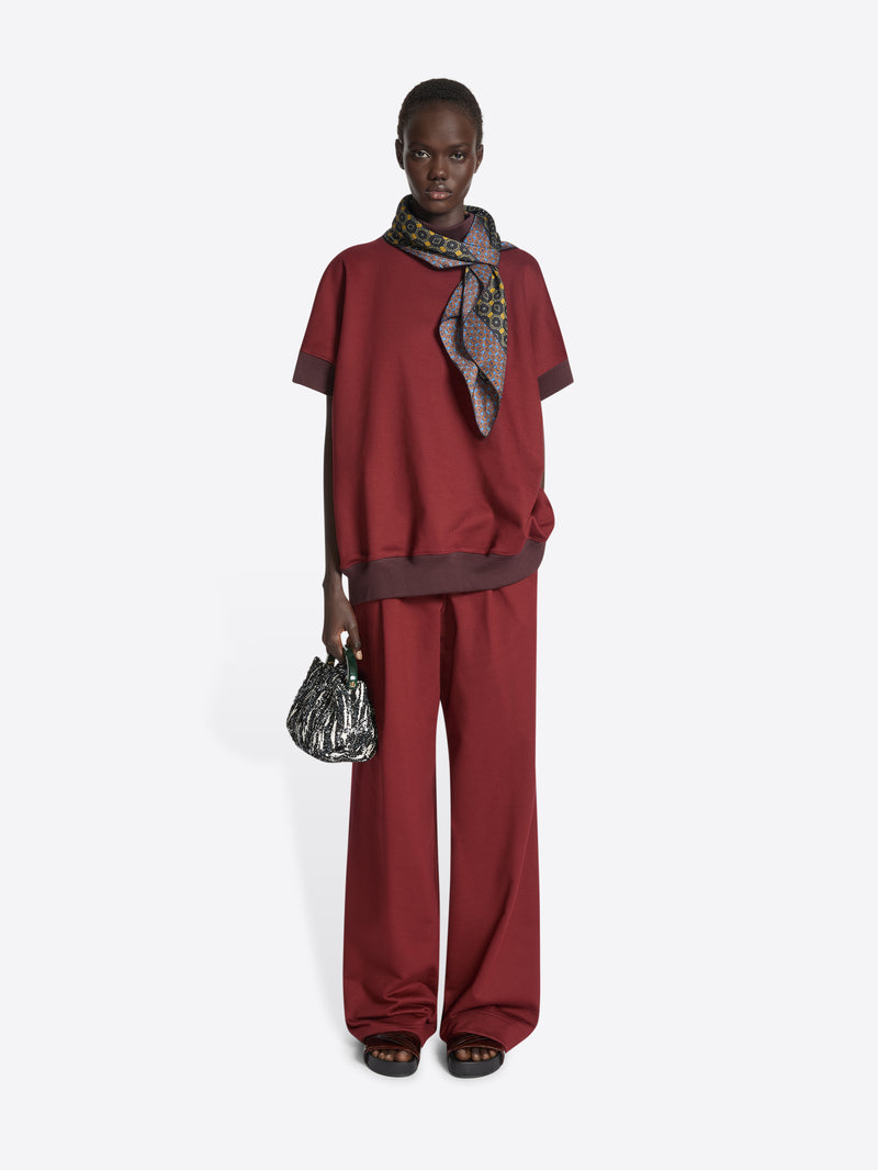 Person wearing a patterned scarf with geometric design on a white background