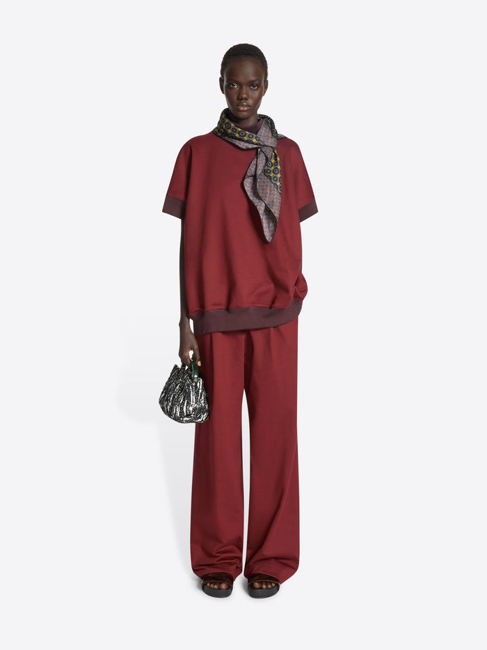 Person wearing a patterned scarf with geometric design on a white background