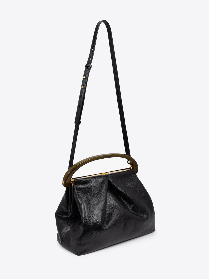 Black pleated leather bag with brown resin handle and a long, thin strap on a white background