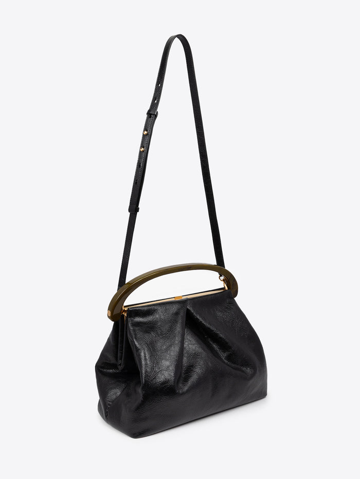 Black pleated leather bag with brown resin handle and a long, thin strap on a white background