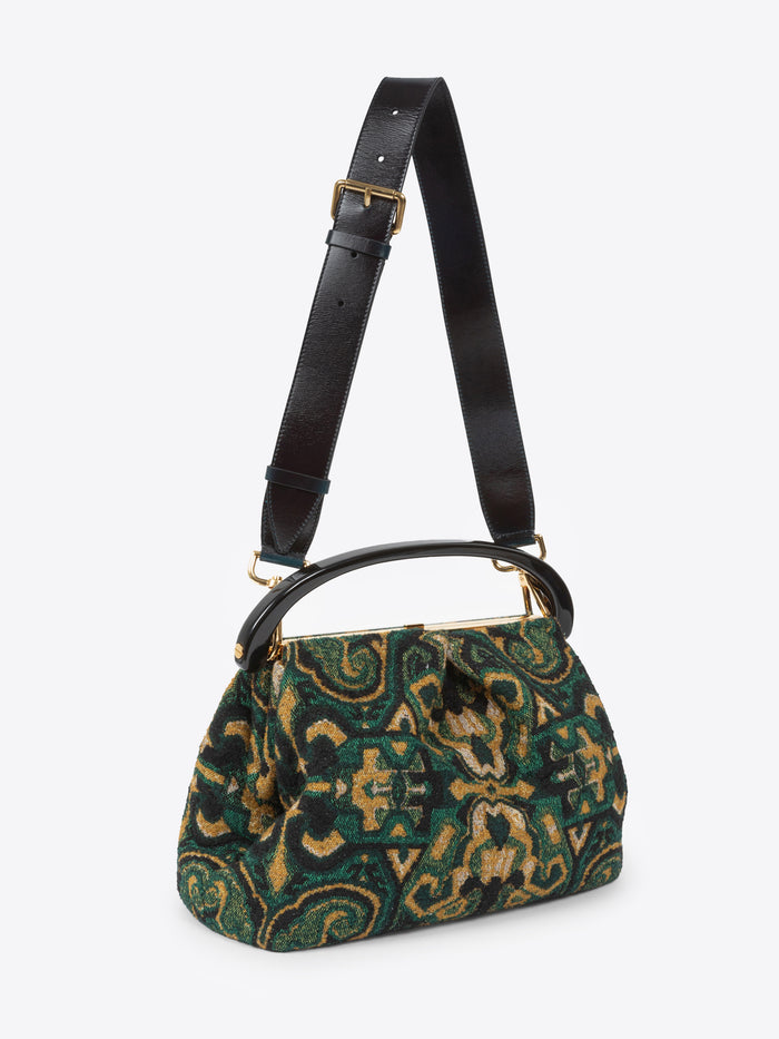 Pleated jacquard bag with green, yellow and black design with a thick black strap on a white background