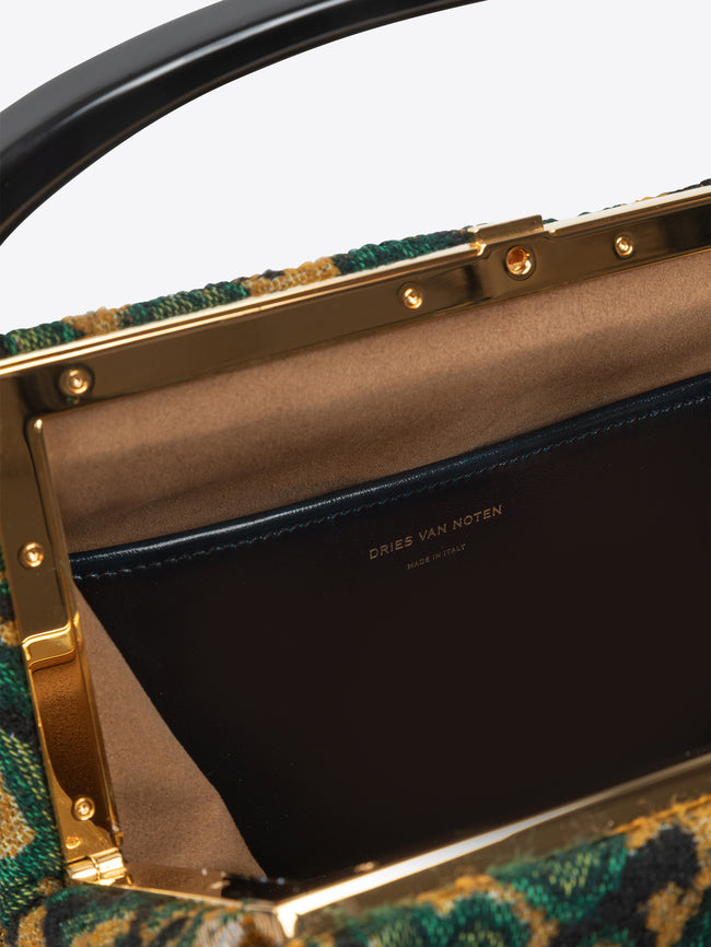 Close-up of a green patterned handbag with gold accents and Dries Van Noten Label on a white background