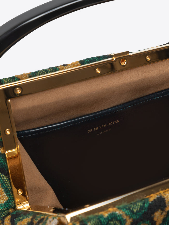 Close-up of a green patterned handbag with gold accents and Dries Van Noten Label on a white background