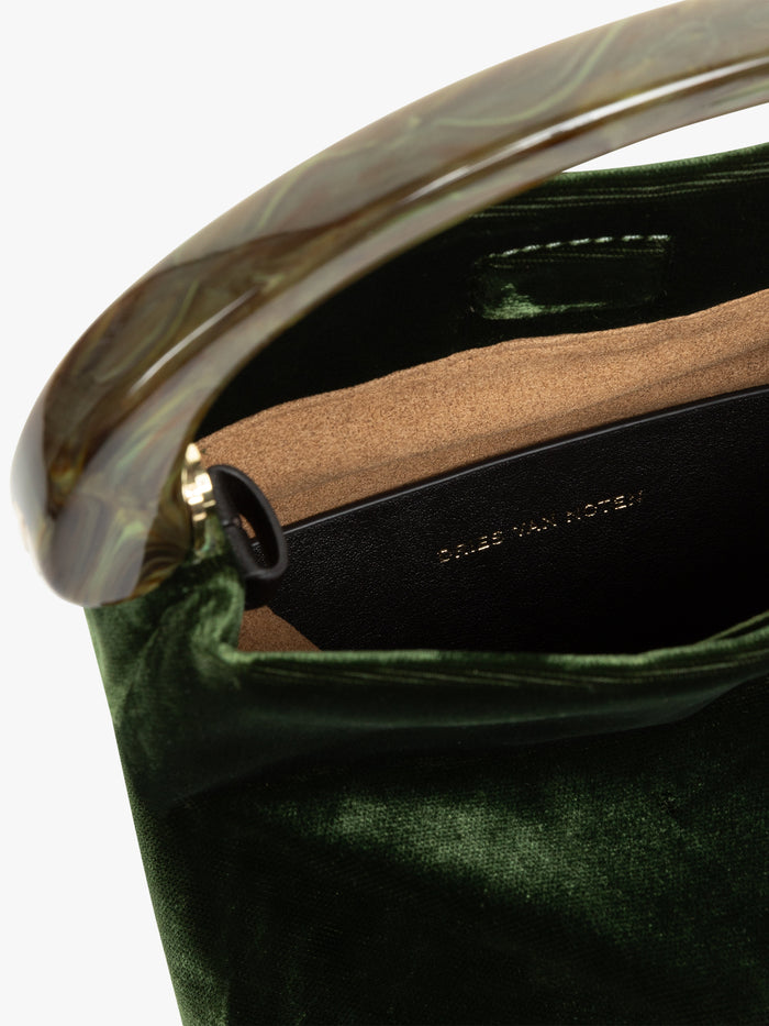 Close-up of a green handbag with a gold handle and visible brand name.