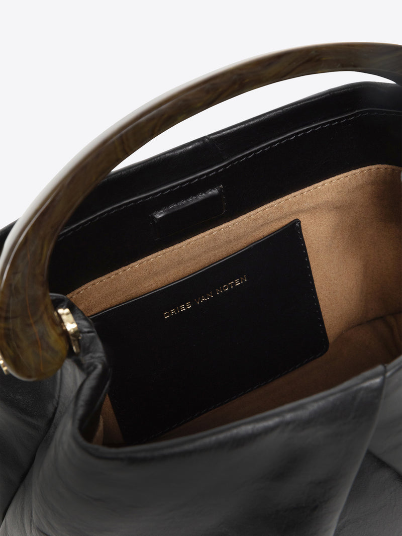 Close-up of the inside of a leather handbag with a Dries Van Noten label on a white background